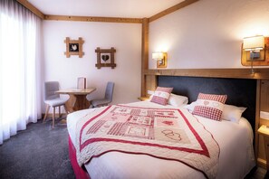 A hotel room with a large bed, a desk, and two chairs. - Logis Hôtel le Littoral (Evian-les-Bains)