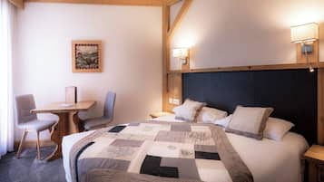 A hotel room with a large bed, a desk, two chairs, and two wall-mounted lamps.