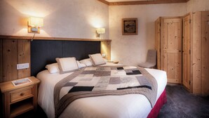 A bedroom with a large bed, wooden headboard, two bedside tables, a nightstand, a wall-mounted lamp, a framed picture, and a wardrobe. - Logis Hôtel le Littoral (Evian-les-Bains)