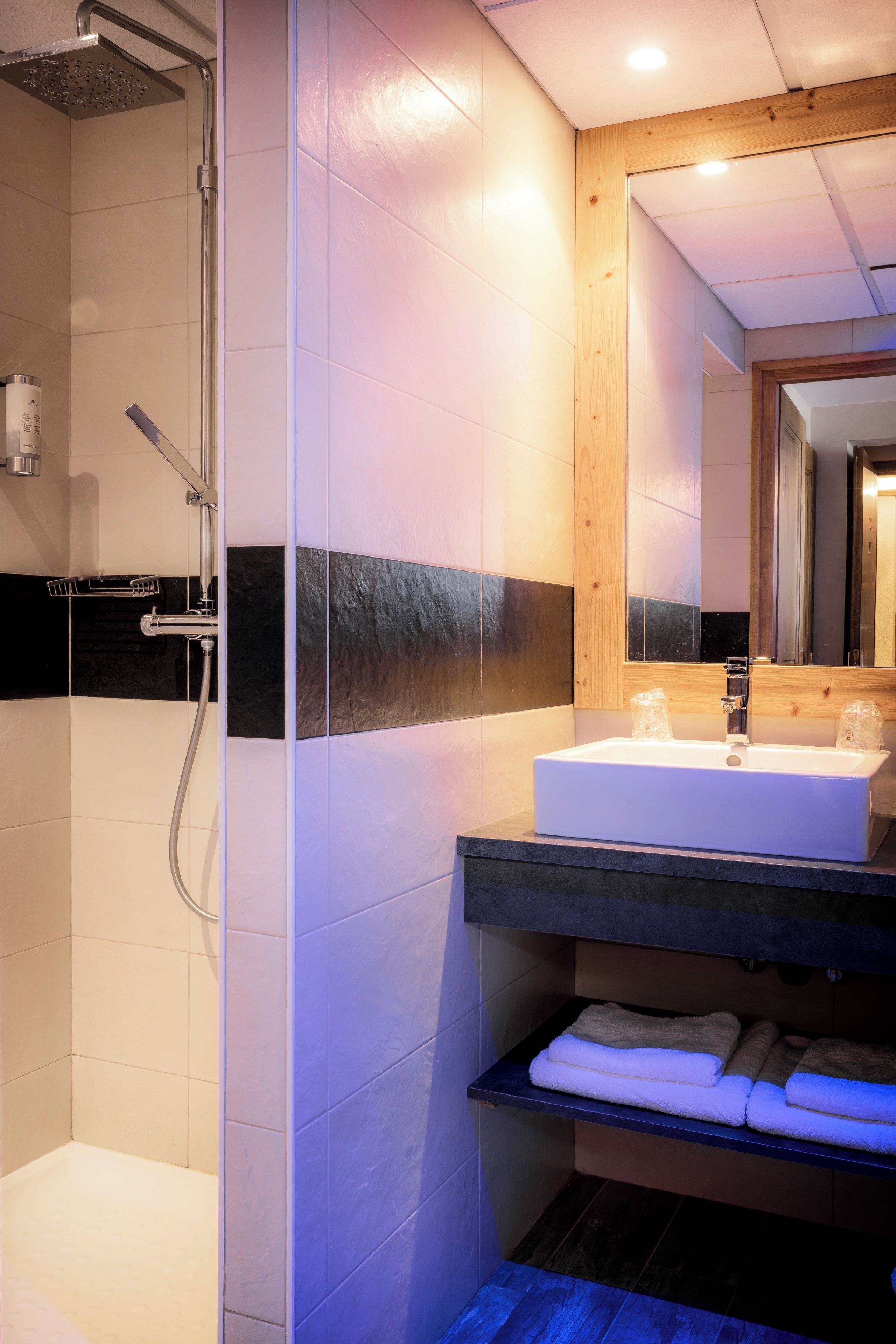 A modern bathroom with a shower, a sink, and a mirror.