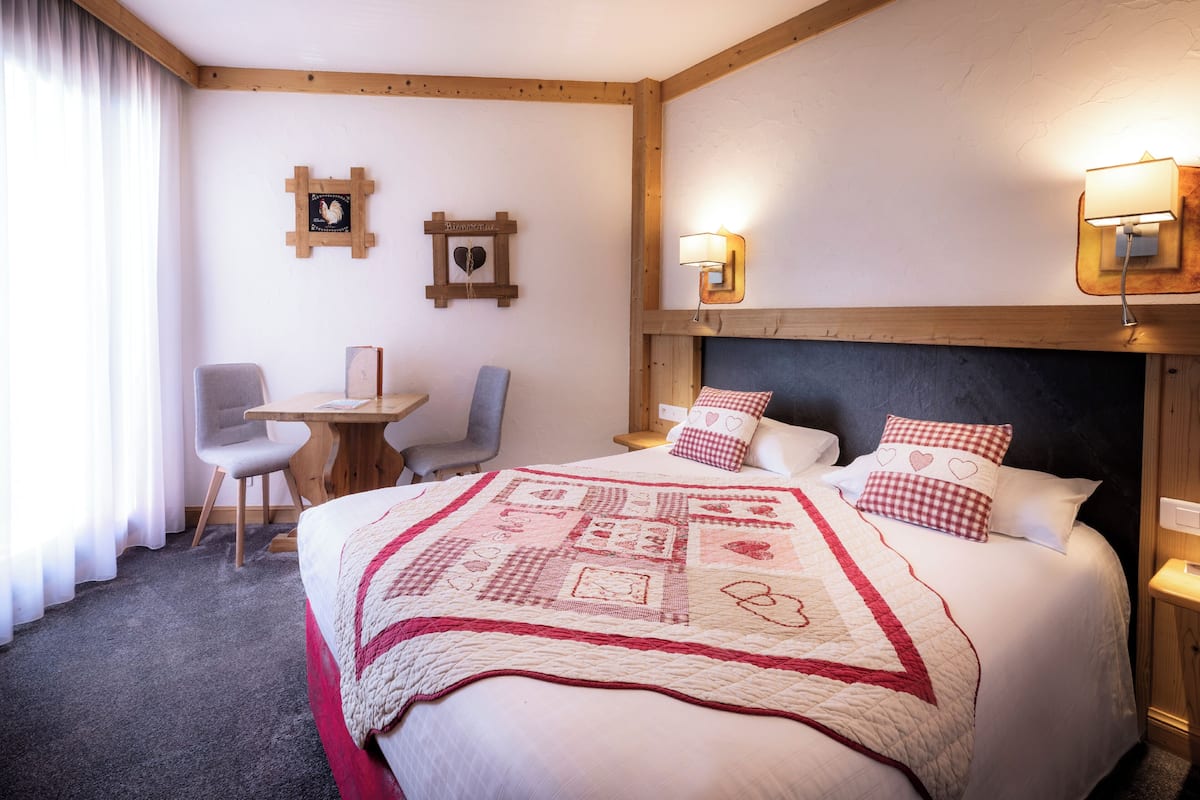 A hotel room with a large bed, a desk, and two chairs.