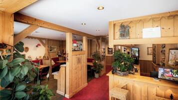 Un interior de fusta amb taulell de recepció, zona de seients i diversos objectes decoratius.