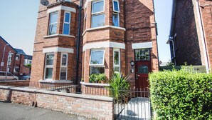 A red brick terraced house with bay windows, a front door, and a small garden. - Glandore Lodge (Belfast)