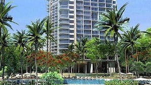 A high-rise hotel with a pool area surrounded by palm trees. - NorthPoint Pattaya with Sea View (Pattaya)