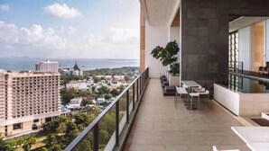 A balcony with a view of a cityscape, including a tall building and a body of water. - NorthPoint Pattaya with Sea View (Pattaya)
