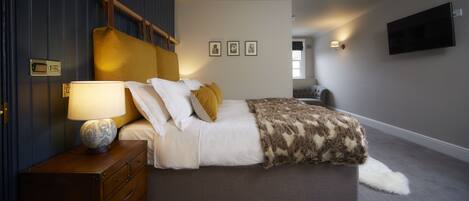 A modern bedroom with a bed, bedside table, lamp, and wall-mounted artwork.