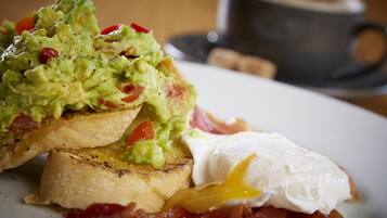 A breakfast plate with toast, avocado, bacon, and a poached egg.