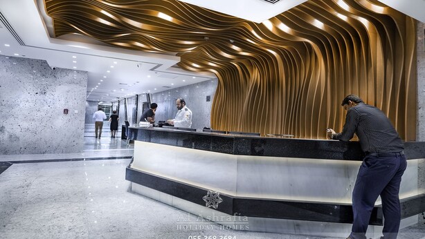 Uma área de recepção de hotel moderna com um balcão curvo, piso de mármore e um design de teto de madeira exclusivo.