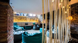 A cozy living area with a stone wall, a sofa set, and a hanging light fixture. - Mountain Hostel Tarter (El Tarter)