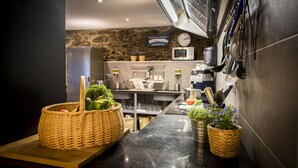 A modern kitchen with a stone wall, stainless steel appliances, and a wooden counter. - Mountain Hostel Tarter (El Tarter)