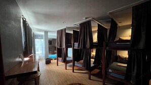 A dorm-style room with bunk beds, a wooden table, and a small round table. - West Coast Beach House (Moalboal)