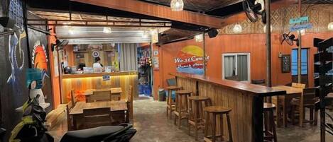 Un espace de restauration intérieur avec un bar, des meubles en bois et un comptoir où une personne sert les clients.