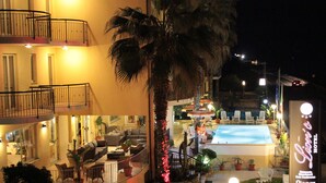 Un hotel con piscina, mobiliario exterior y un letrero de neón.