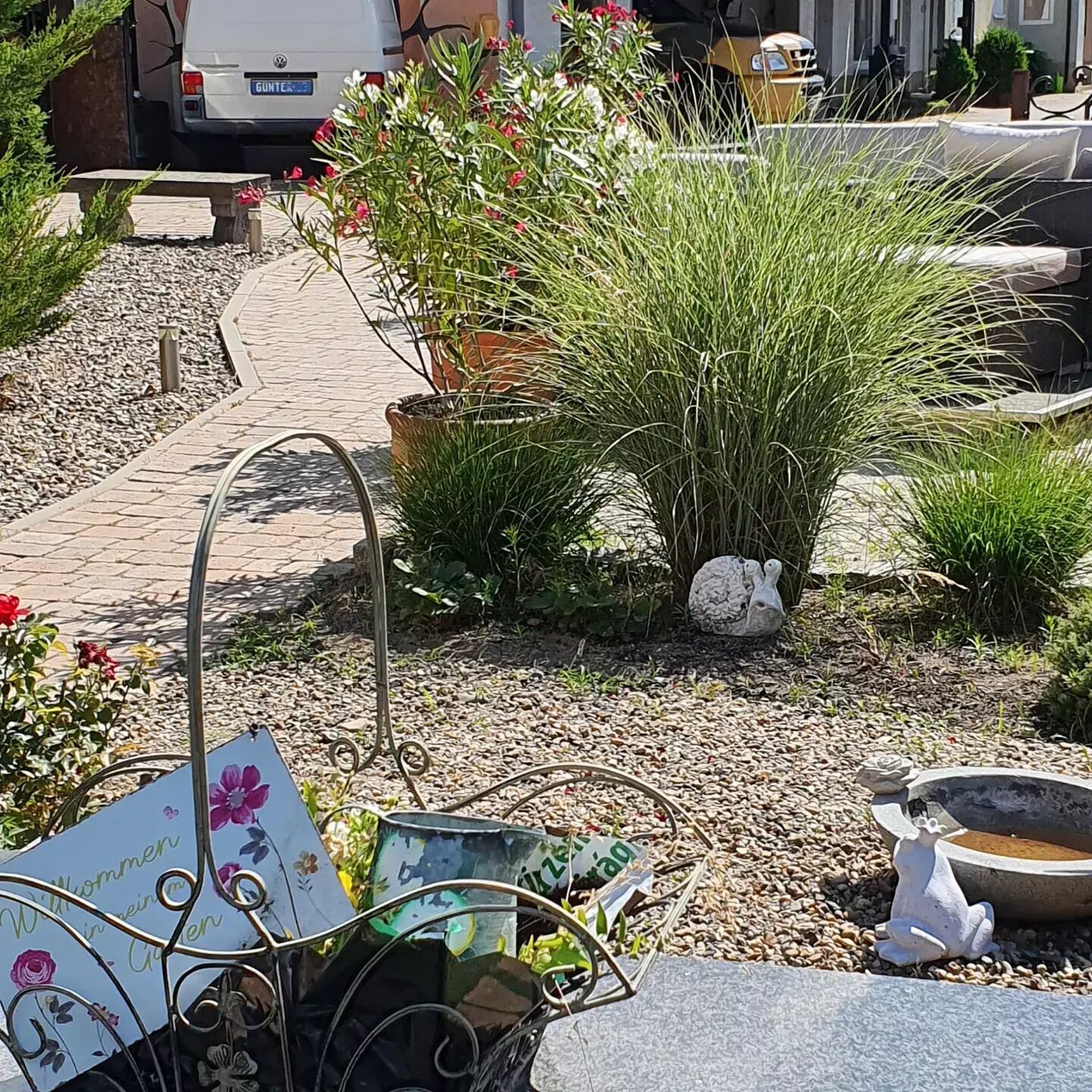 A garden area with a pathway, potted plants, and a metal sculpture.