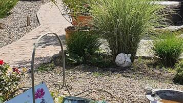 A garden area with a pathway, potted plants, and a metal sculpture.