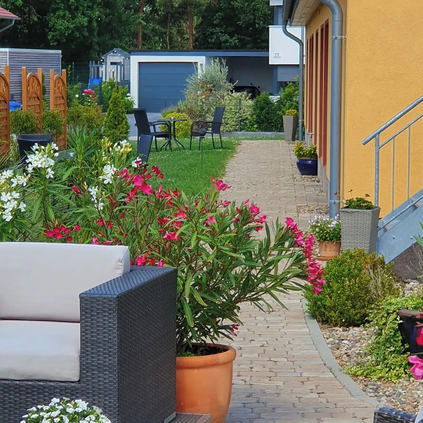 Een tuinpad dat leidt naar een gebouw met terras en een garage.