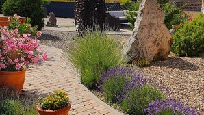 A garden pathway with potted plants and a stone statue. - Apartmenthaus in Walle (Schwülper)