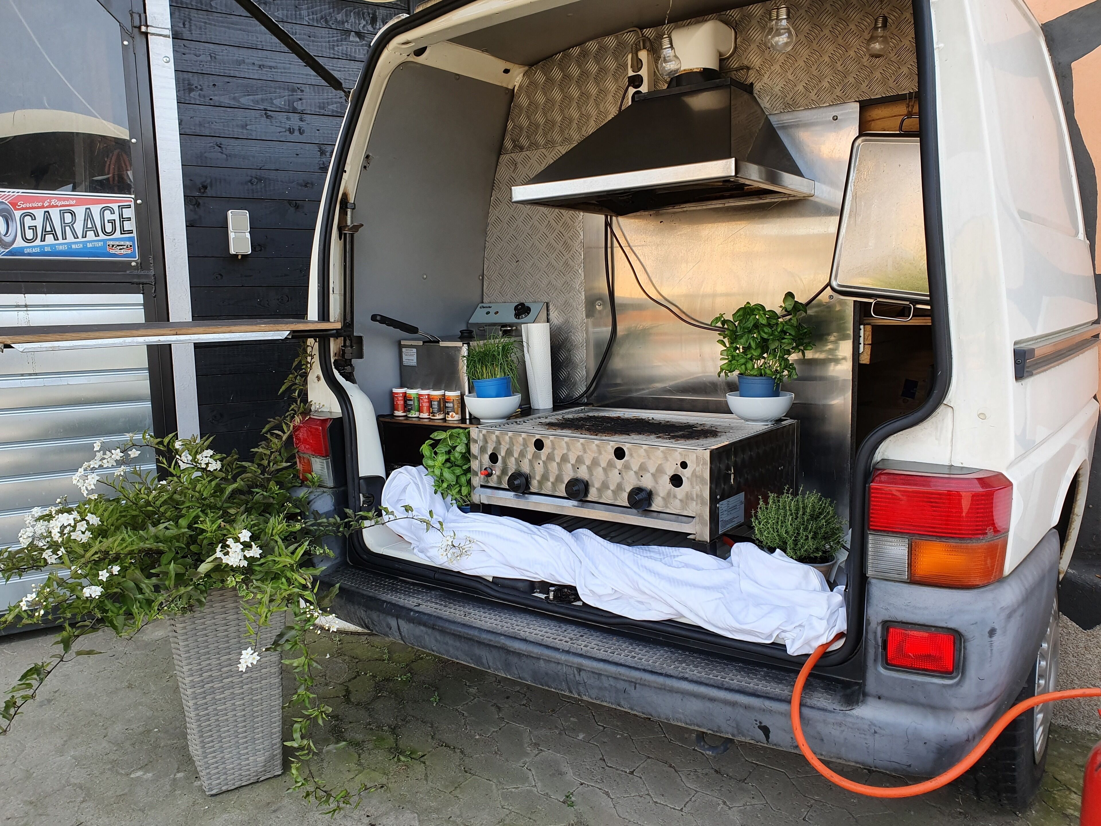 Ein Van mit einer Küchenzeile, einem Bett und einem kleinen Garten.