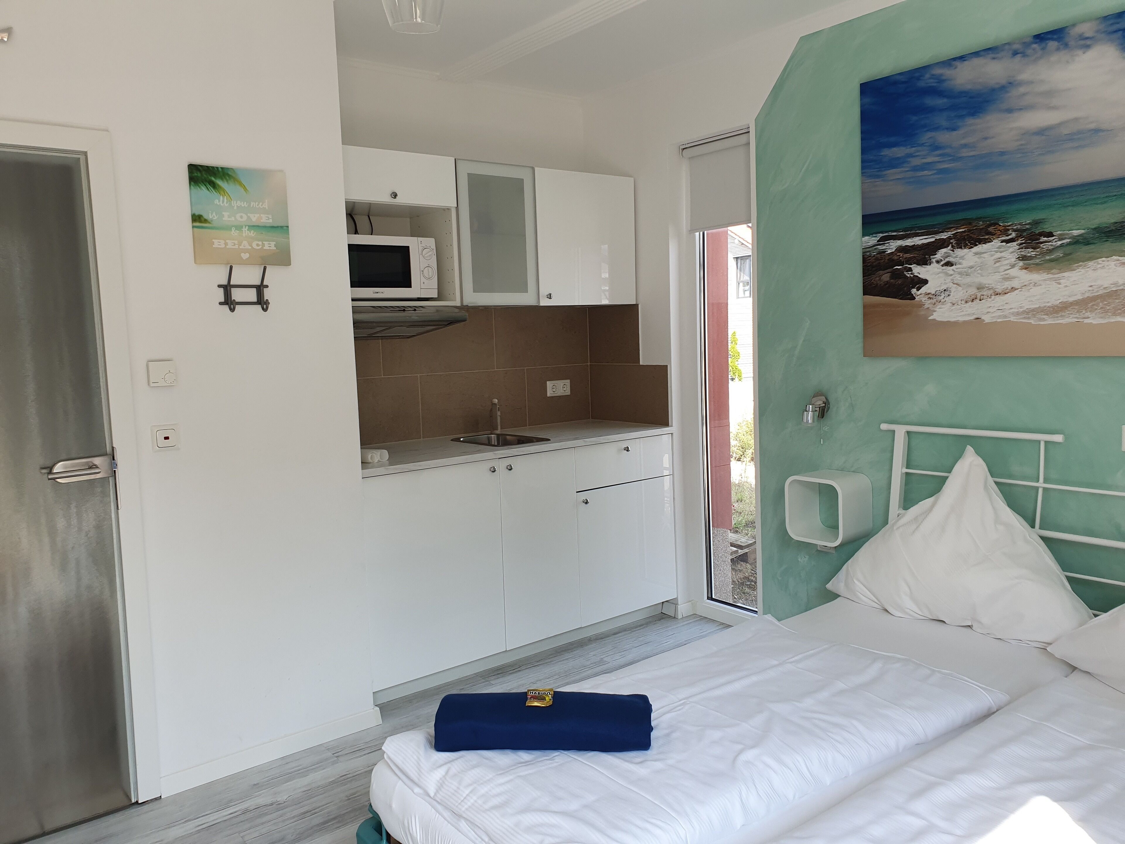 Un dormitorio pequeño con cama, kitchenette y vista al mar.