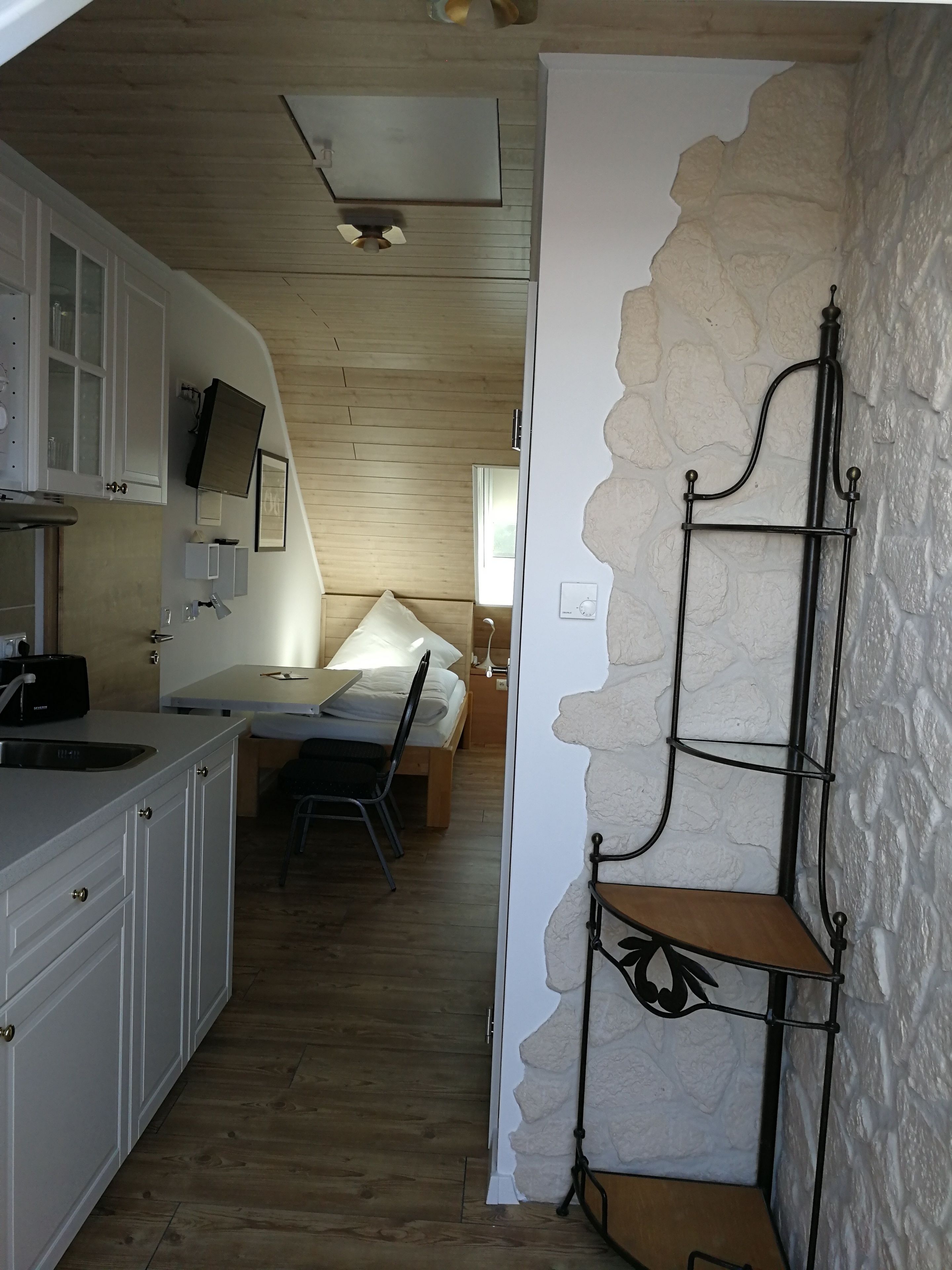 Cocina compacta con armarios blancos, encimera de madera y un pequeño comedor con mesa y sillas.