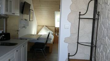 Cocina compacta con armarios blancos, encimera de madera y un pequeño comedor con mesa y sillas.