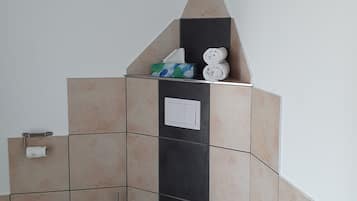 A bathroom with a toilet, a towel rack, a tissue box, and a saltwater cure sign.