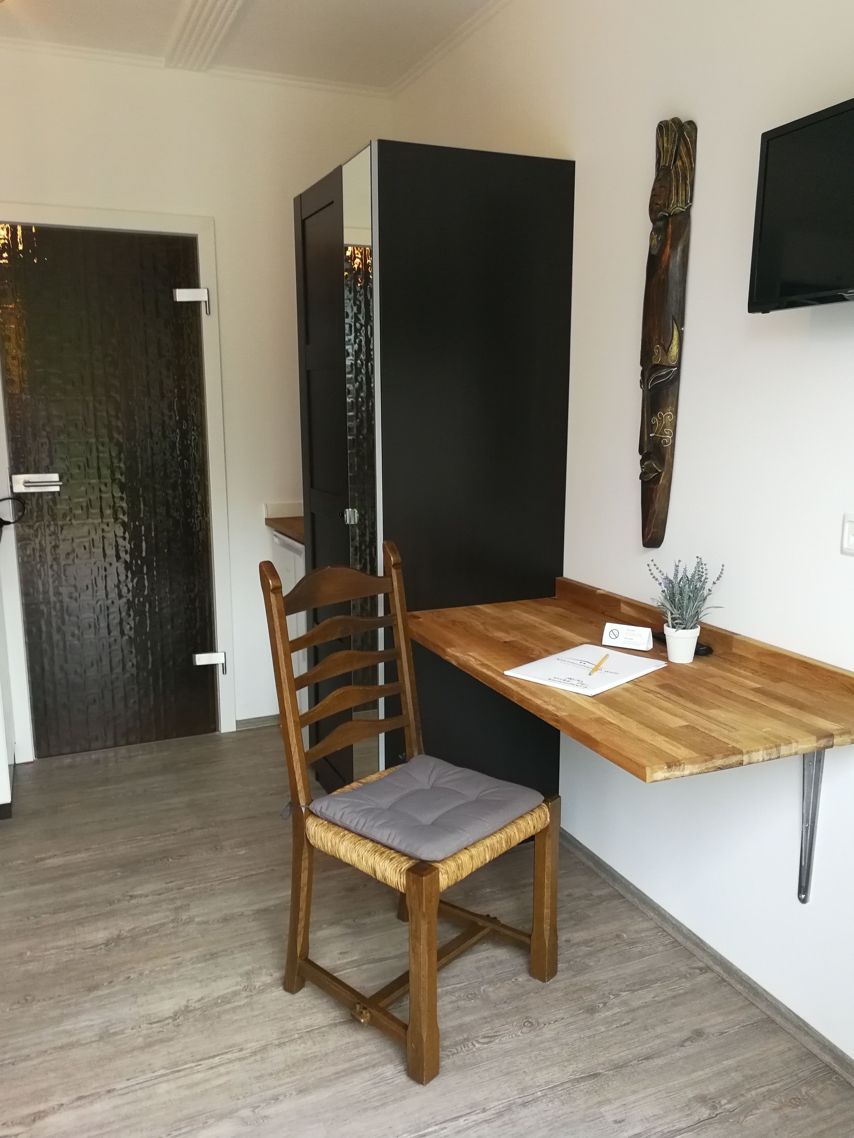 Une cuisine moderne avec une table à manger en bois, une chaise et une sculpture décorative en bois accrochée au mur.