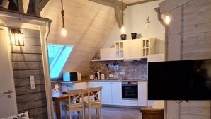 A cozy loft-style living space with a loft bed, a dining area, and a kitchen with white cabinets and a stone backsplash. - Apartmenthaus in Walle (Schwülper)