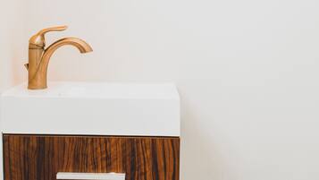 Un baño con un tocador de madera, un lavamanos blanco y un cajón.