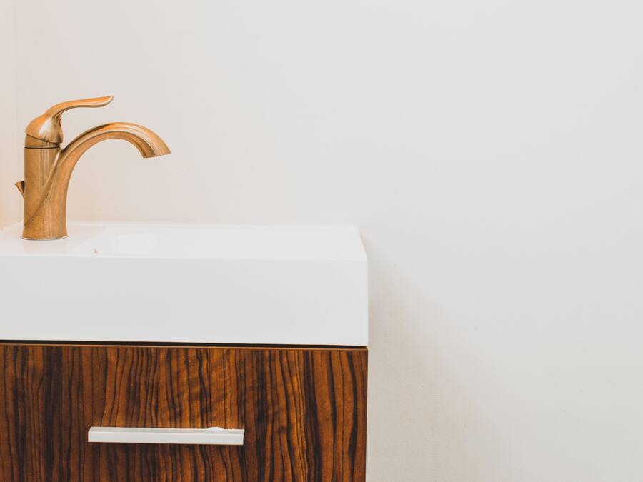 Un baño con un tocador de madera, un lavamanos blanco y un cajón.