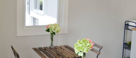 Un comedor con mesa de madera y bancos, una ventana con persianas y un ordenador portátil sobre la mesa.