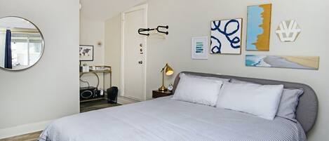 Un dormitorio con una cama grande, un espejo redondo y obras de arte en las paredes.