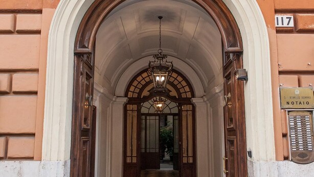 A grand entrance with a marble floor, an arched doorway, and a chandelier. - Lifestyle Veneto Suite (Rome)