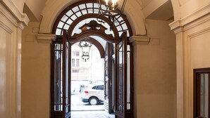 A hallway with a checkered floor, an arched doorway, and a chandelier. - Lifestyle Veneto Suite (Rome)