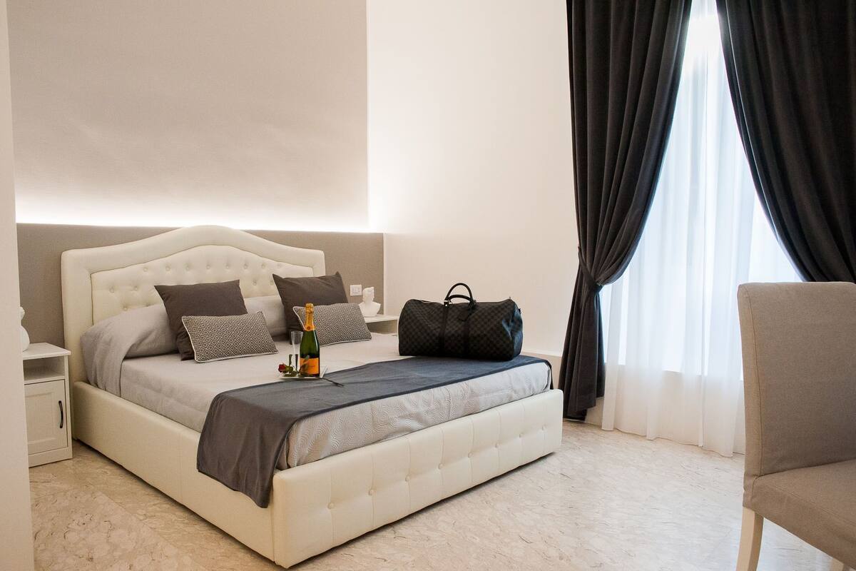 A neatly arranged bedroom with a bed, bedside table, and a chair.