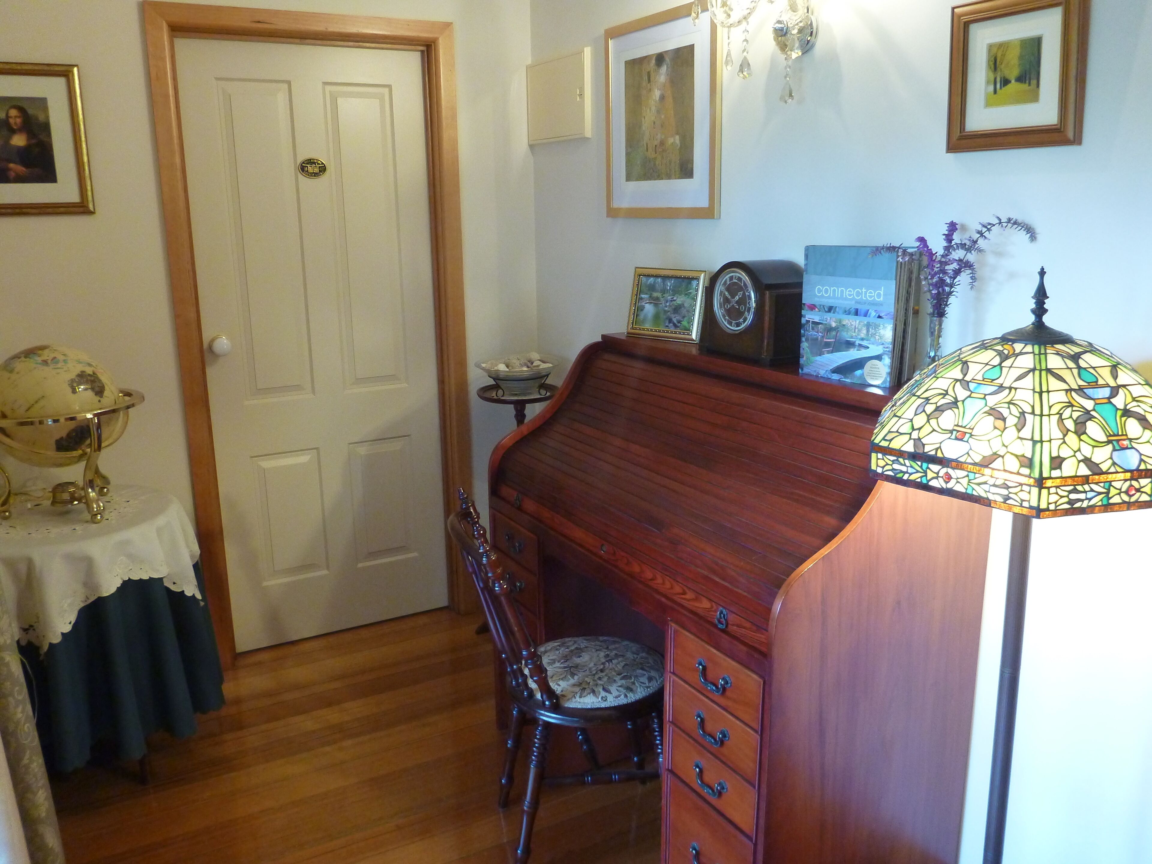 Una habitación con un escritorio de madera, una silla, un globo terráqueo sobre una mesa y una lámpara.