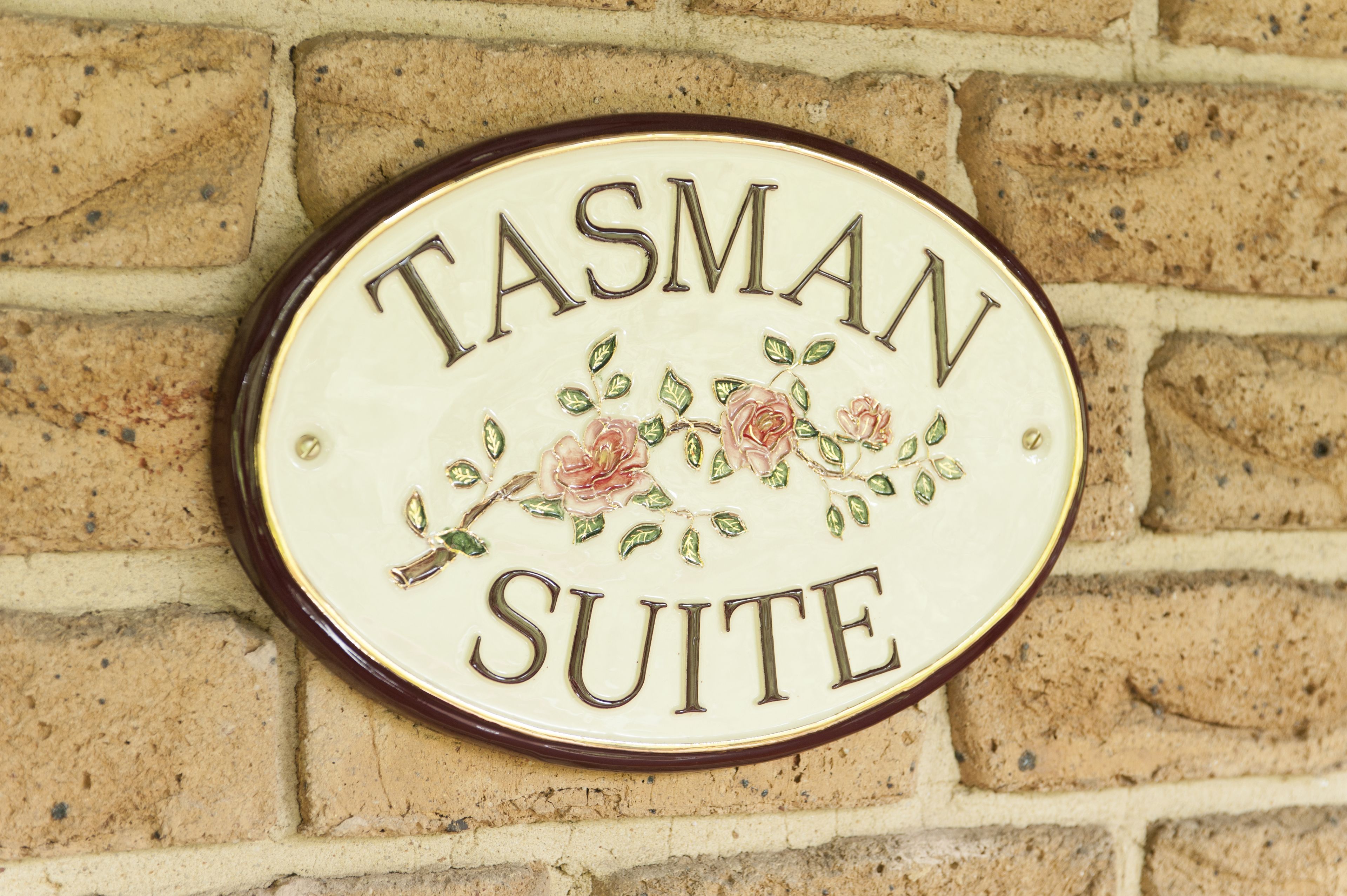 Et skilt med teksten "TASMAN SUITE" på en murstensvæg.