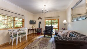 A living room with a fireplace, a television, a sofa, and a dining area with a table and chairs. - Mountain Lodge (Mount Dandenong)