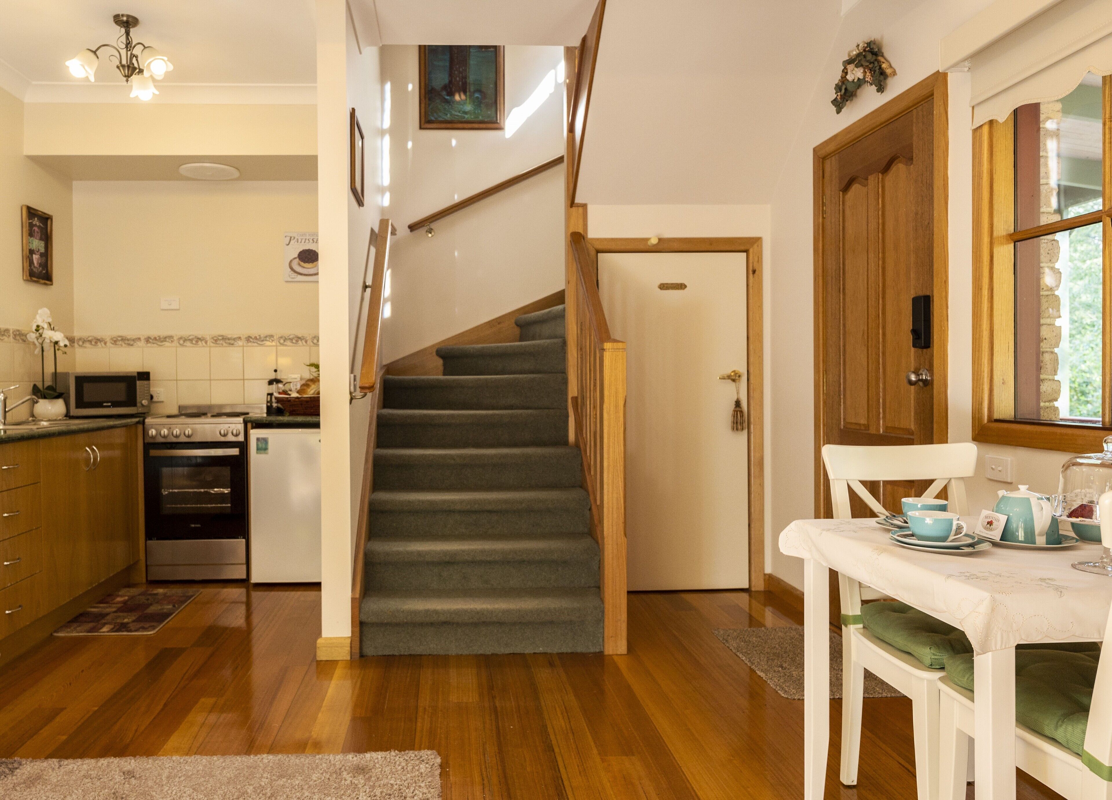 A kitchen with wooden cabinets, a microwave, an oven, and a dining area with a table set for two.