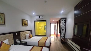 Camera d'albergo con due letti, una televisione e un bagno visibile attraverso una porta in vetro.