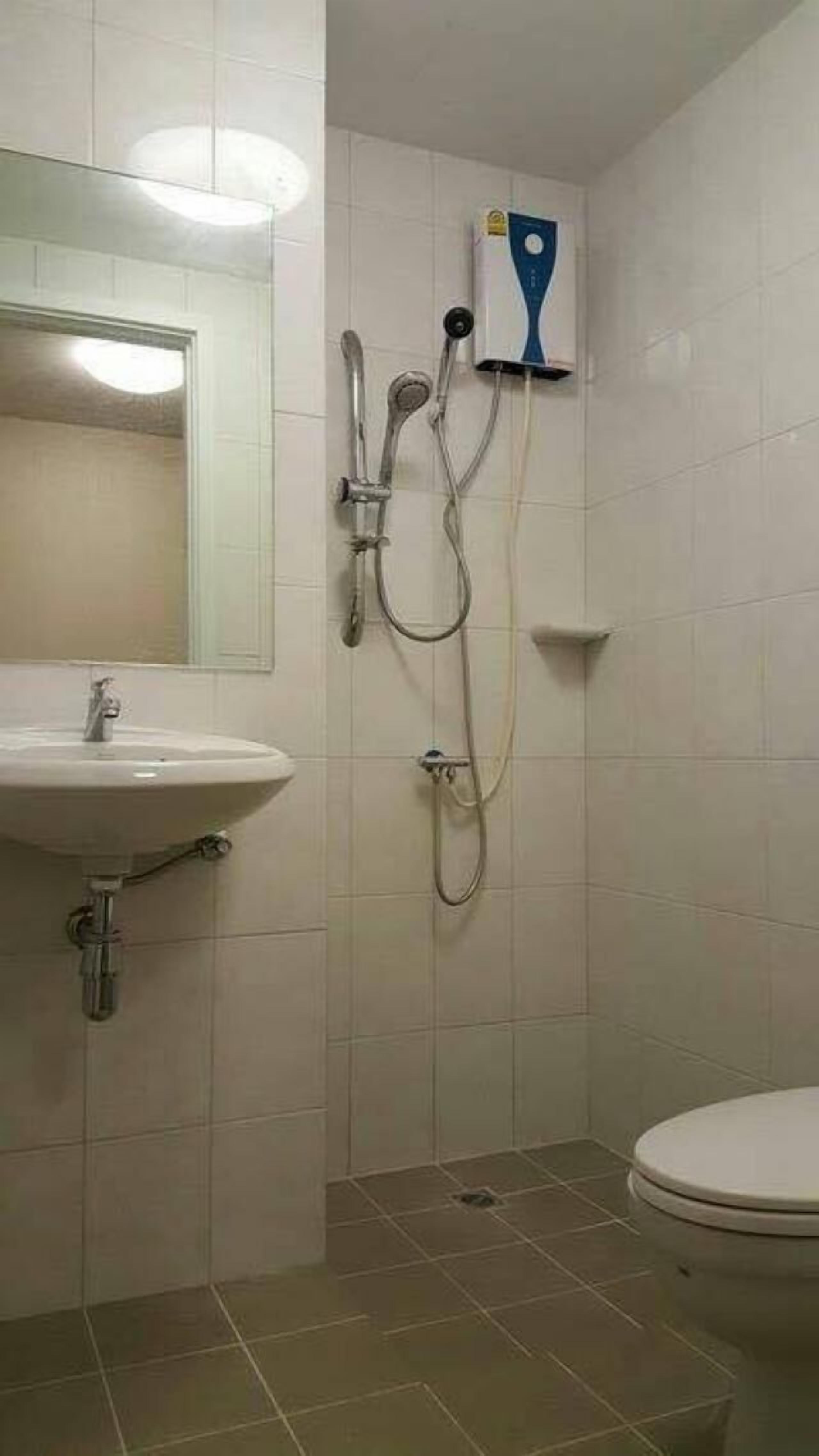 A bathroom with a sink, mirror, shower, and toilet.