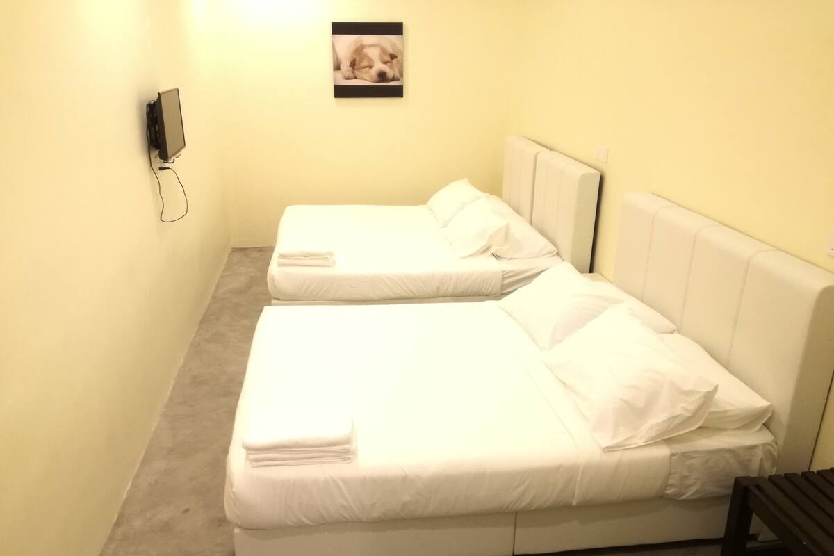A room with two single beds, a small desk, and a picture on the wall.