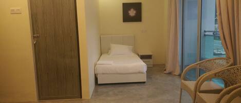 Habitación de hotel con cama, una silla, una puerta y una ventana con cortinas.
