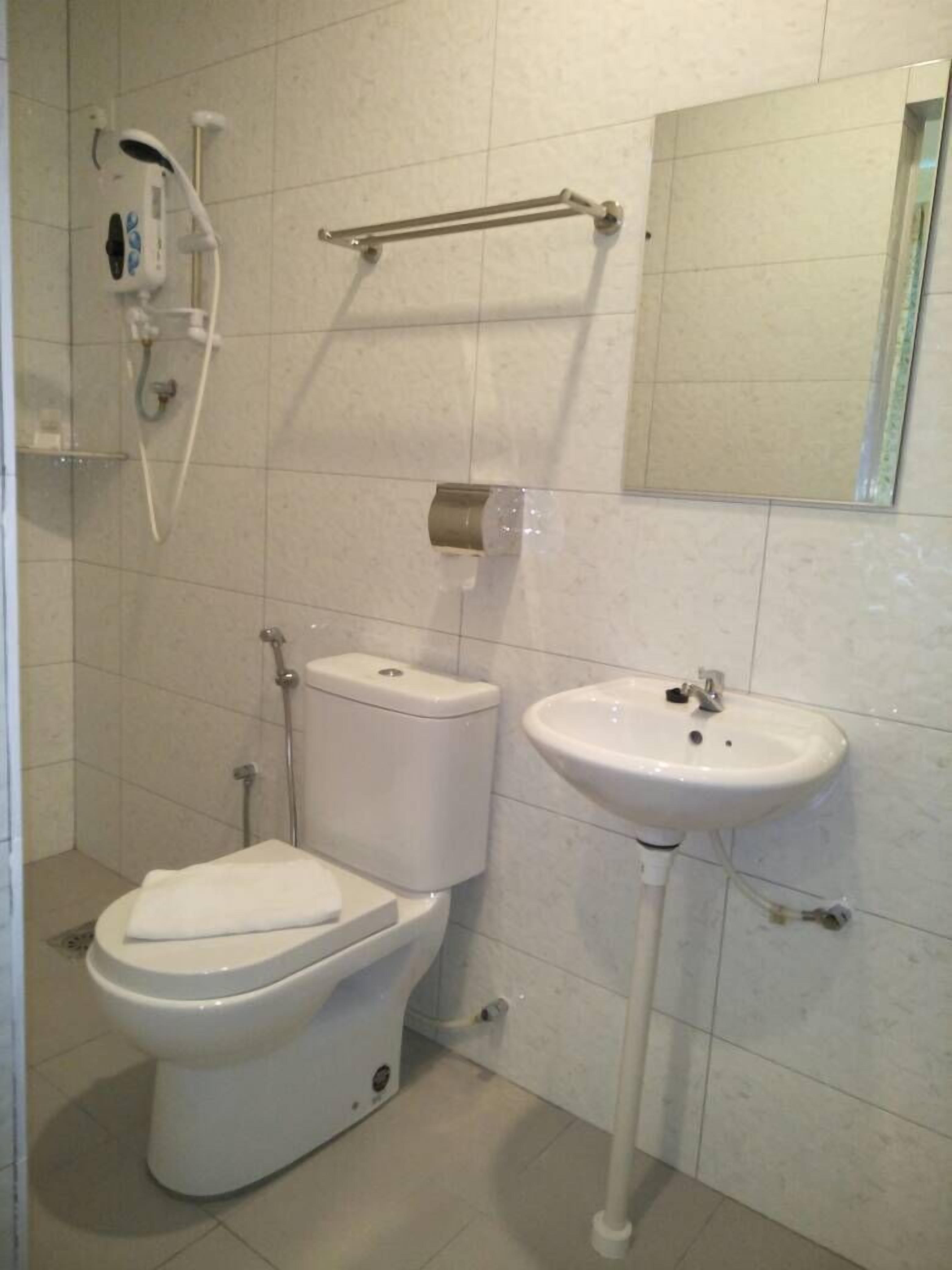 Une salle de bain équipée de toilettes, d’un lavabo, d’une douche et d’un sèche-mains.