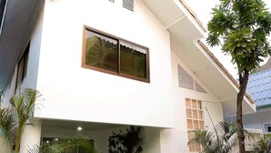 Ein modernes, zweistöckiges Haus mit einem großen Fenster, einer Treppe und mehreren Kübelpflanzen.