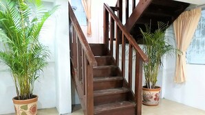 Eine Holztreppe mit Handlauf, gesäumt von Blumentöpfen.
