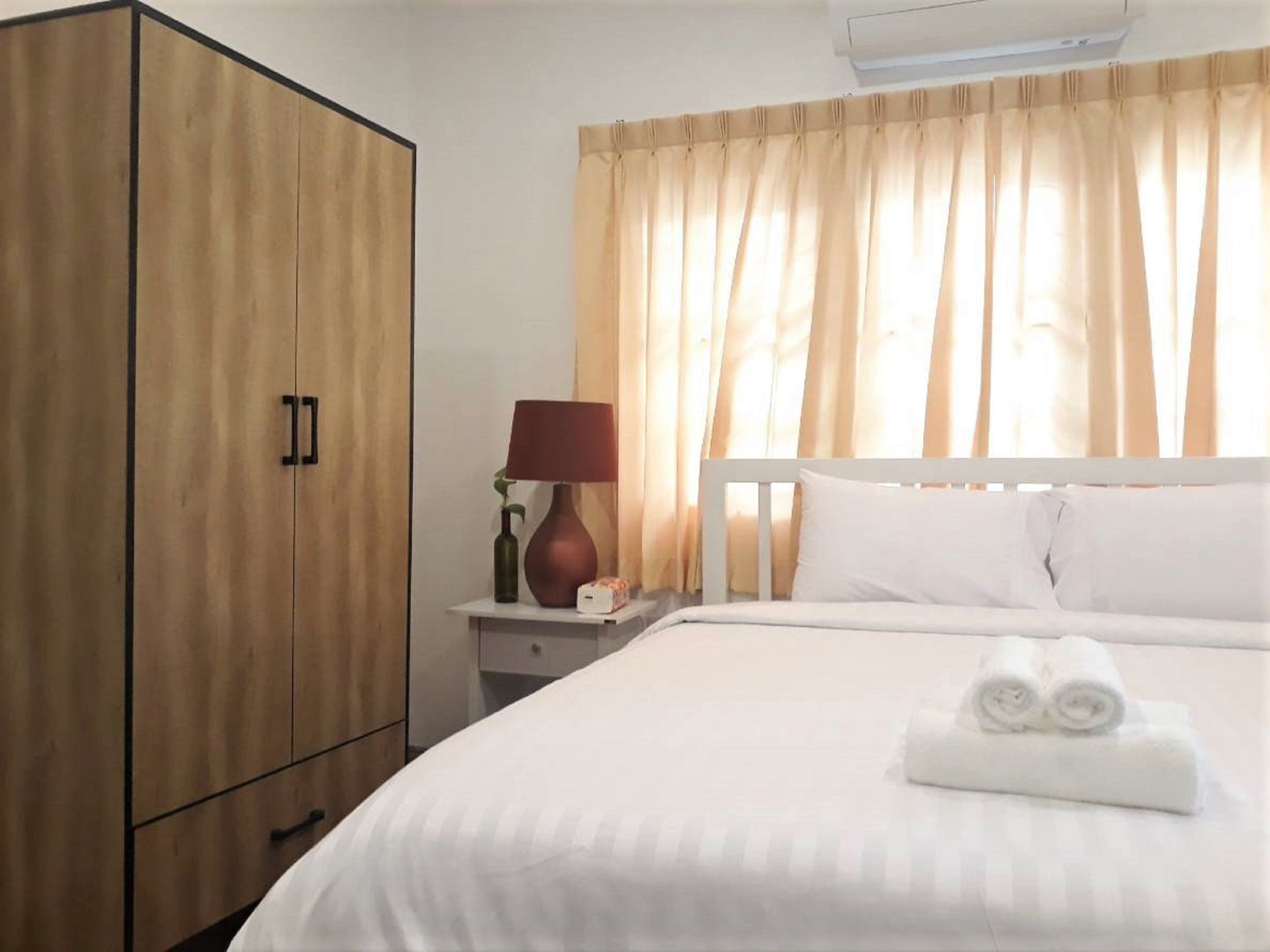 Una habitación de hotel con una cama, una mesita de noche, una lámpara y un armario.