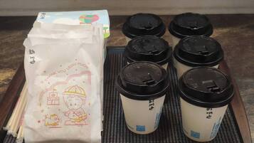 A tray with six disposable cups and a paper bag with a cartoon character and text.