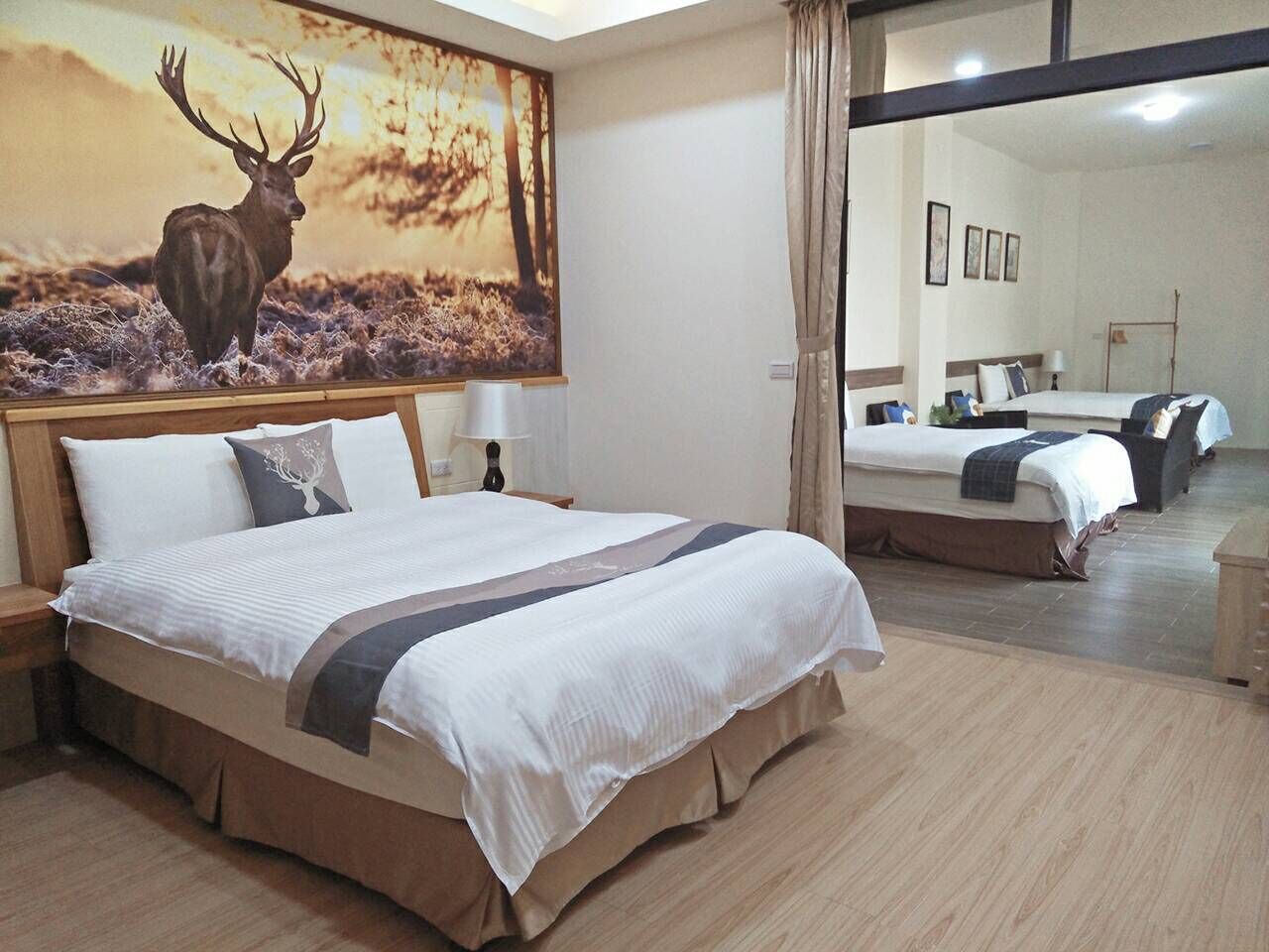 A hotel room with a large bed, a mirror, and a painting of a deer.