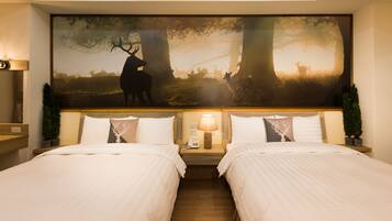 A hotel room with two beds, a large forest-themed mural on the wall, a nightstand with a lamp, and a small potted plant.